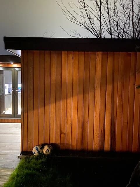 Warm lighting on the timber exterior of a garden room at night
