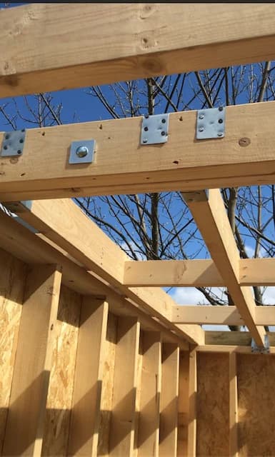 Roof joists fixed with metal plates above the timber stud walls, open to the sky