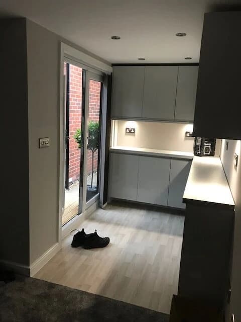 Compact kitchen area with grey cabinetry, a sink and a glazed garden door